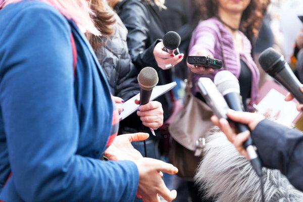 Public figure talking to the media, journalists holding microphone