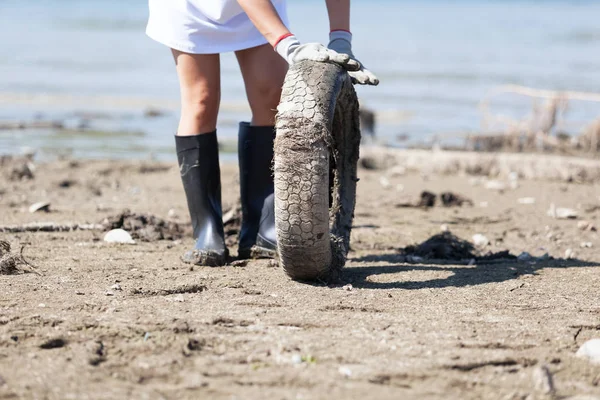 Activista ambiental está recogiendo neumáticos viejos en la costa del río o lago —  Fotos de Stock