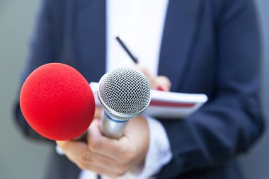 Basın konferansında ya da medya etkinliğinde kadın gazeteci, notlar yazma, mikrofon tutma