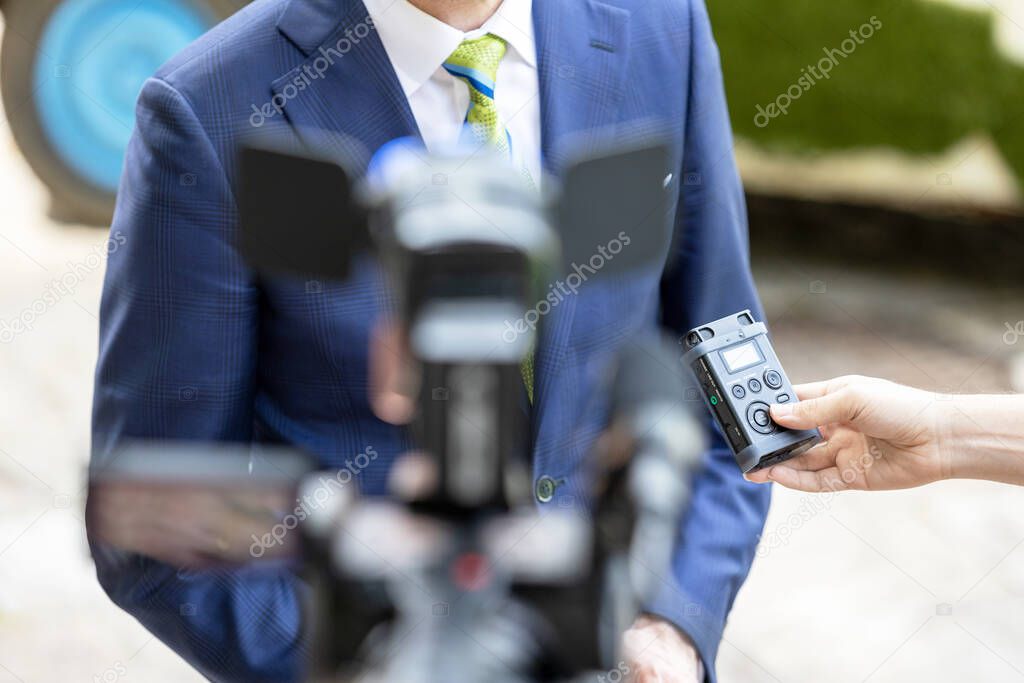 Reporter holding voice recorder making media interview with politician or business person