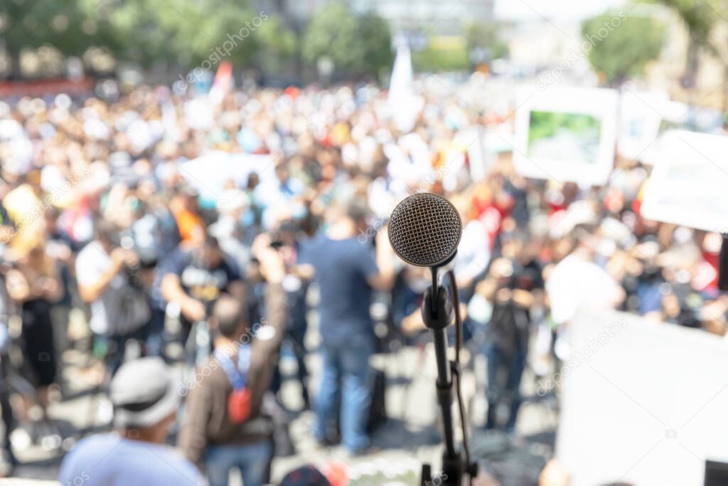Public demonstration or political protest. Microphone in focus against unrecognizable crowd of people.