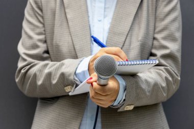 Basın konferansında ya da medya etkinliğinde kadın muhabir, notlar yazma, mikrofon tutma. Gazetecilik kavramı.