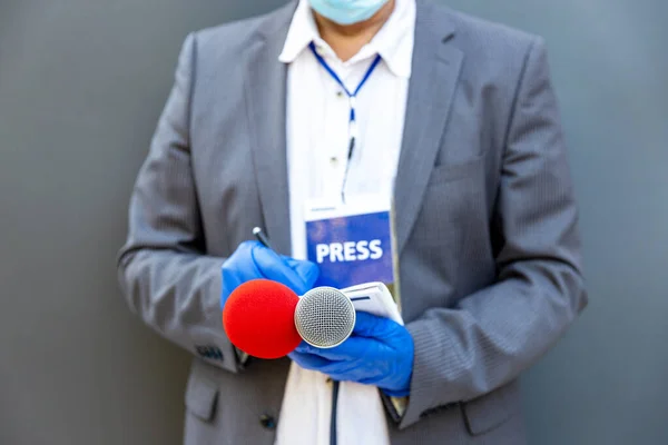 Reporter at press conference or media event wearing protective gloves and face mask against coronavirus COVID-19 disease