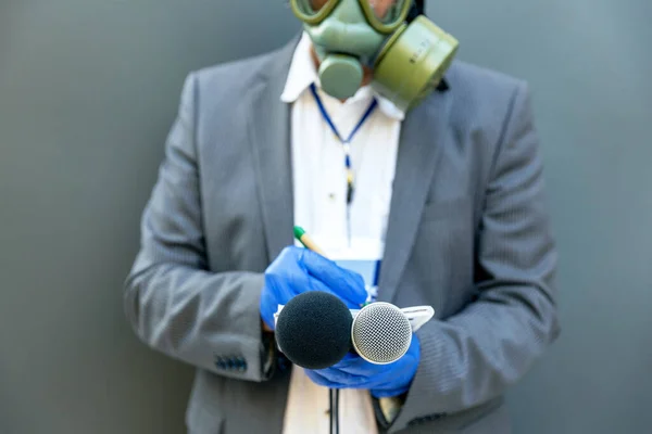 Journalist at news conference or media event wearing protective gloves and face mask against coronavirus COVID-19 disease holding microphone writing notes
