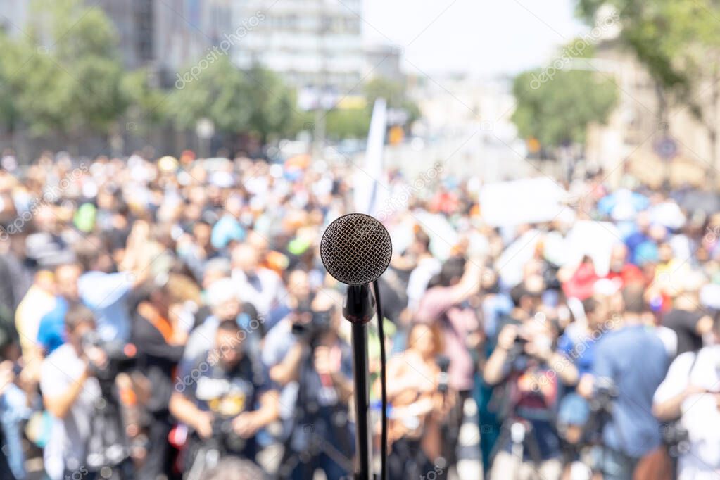 Public demonstration or political protest. Microphone in focus against unrecognizable crowd of people.