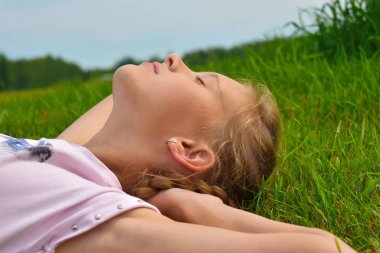 Yazın yeşil çimenlerin içinde güzel küçük bir kız. Ha yüzü