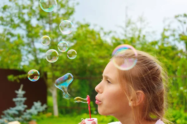 Krásná holka nafuí mýdlové bubliny. Veselý šťastný krok v t — Stock fotografie