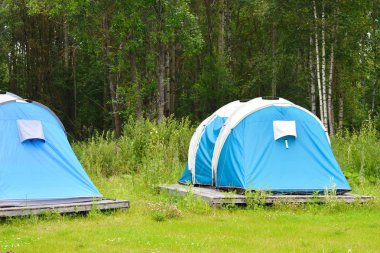 Ormanda mavi çadır. Dışarıda kamp var. Dinlenmek için turist kamp. Tatil için kiralık çadırlar.