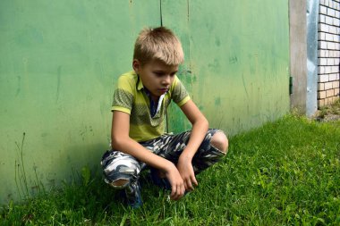 rahatsız ve kızgın çocuk stree üzerinde yaz aylarında bir duvara oturur