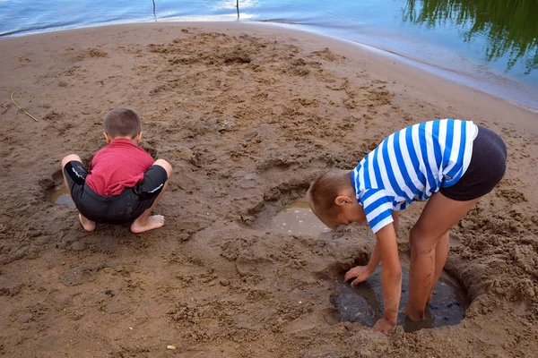 Jongen speelt vuil op de oever van de rivier in de zomer. Actieve Kinder h — Stockfoto