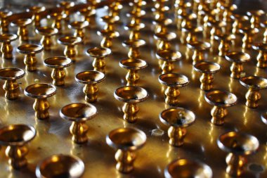 Tapınakta kilise mumları için altın destekler.