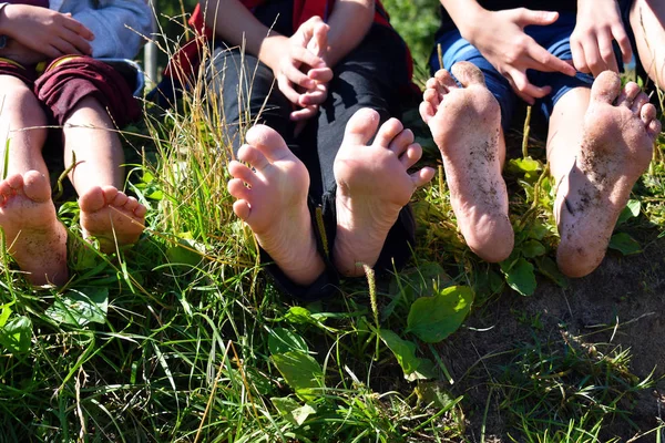Children's naked feet of legs outdoors. Children sit on a grass — Stock Photo, Image