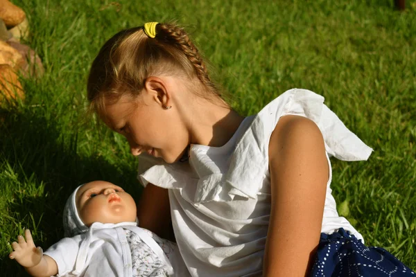 Красивая маленькая девочка с куклой летом в саду — стоковое фото