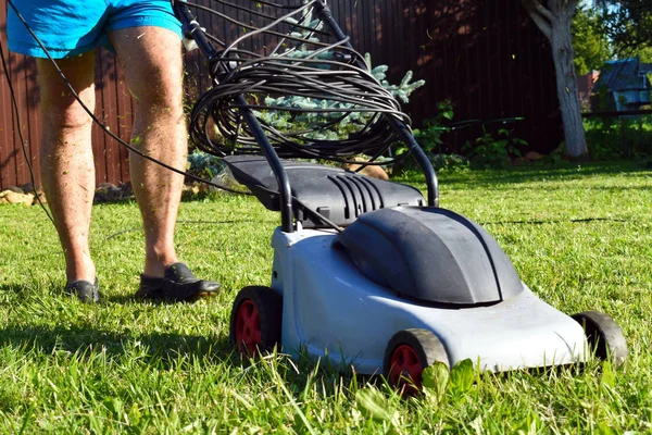 Man klipper grön gräsmatta i trädgården på sommaren. — Stockfoto