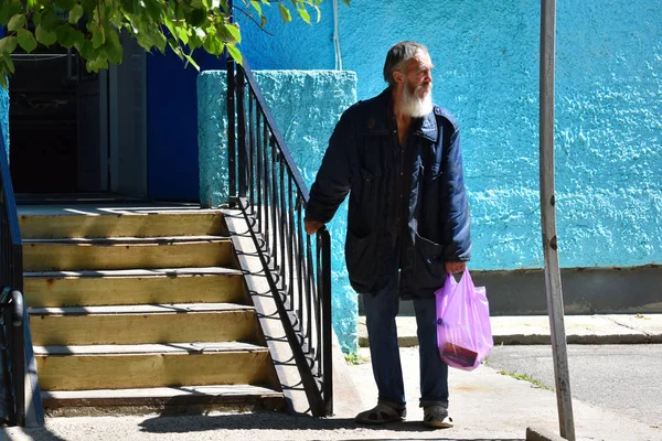 Бедный бездомный старик стоит на входе в магазин — стоковое фото