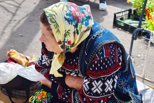 Babcia o pochylił siedzi i czeka na kupującego. — Zdjęcie stockowe