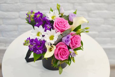 Beyaz bir masa üzerinde şık modern ambalaj pembe güller ile güzel buket. Çiçekçi dükkanı kavramı. Bir tatil için bir kartpostal için romantik buket bir Anneler Günü, Sevgililer Günü. Yakın çekim