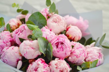 Beyaz bir masada şık modern ambalaj pembe şakayık büyük güzel buket. Çiçekçi dükkanı kavramı. Bir tatil için bir kartpostal için romantik buket bir Anneler Günü, Sevgililer Günü ve Mart 8.