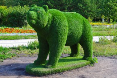 Yeşil otların ayı figürü. Şehir parkında bir figür. Oyun alanında bir şehir dekoru. Yeşil renkli bir ayı heykeli.