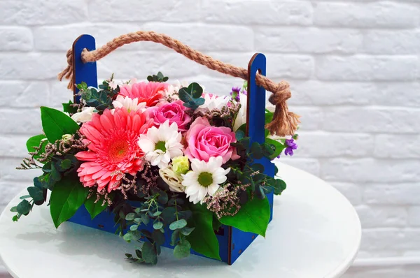 Multi-colored bouquet of flowers in an original basket on a white background. Flower greeting card. Concept of flower shop.