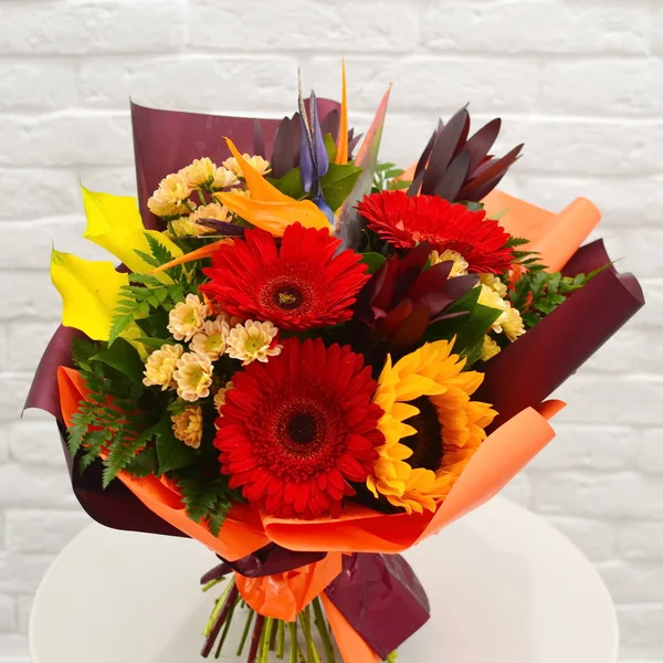 Exotic original bouquet of flowers in stylish packing. The red mixed bouquet of flowers. A concept for flower shop.