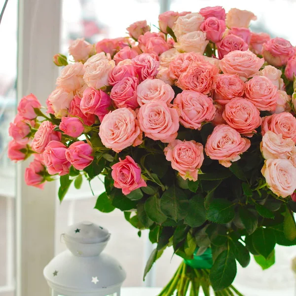 Beautiful lovely bouquet for flower shop. Beautiful bouquet of colorful flowers in packing on white table against the background of brick white wall.  No people.  Close-up.  Concept of flower shop.  Bouquet for catalog.