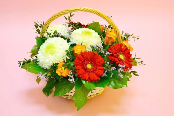 Beautiful flower basket on a table. Beautiful bouquet of colorful flowers in  basket on  table against the background of  brick white wall. No people. Close up. Concept of flower shop. Composition for the catalog.