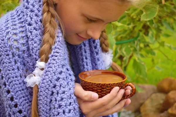 Красивая маленькая девочка в трикотажном одеяле пьет горячий чай . — стоковое фото