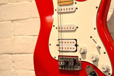 Yırtık telleri ile elektrik kırmızı gitar. Bir tuğla duvarda bir gitar ile Cafe iç.