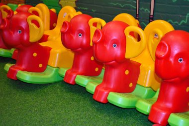 Oyun alanında çocuklar için plastik kırmızı sallanan atlar. Oyuncaklı anaokulu. Çocuklarla eğlence yeri.
