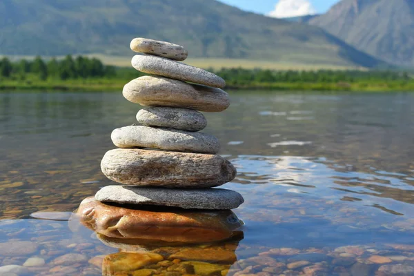 Stones meditation figures. Symbolical statue of several stones. Tradition to collect  stones in private. Beautiful water landscape background with natural stones.