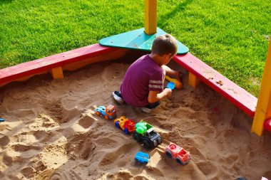 Çocuk yaz aylarında oyuncak figürleri ile oyun alanında bir kum havuzunda oynar. Neşeli çocuk tatili dışında