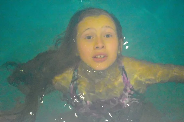 Face of a scared girl underwater. Danger of drowning in the pool. Girl drowning in water. Creepy photo of teenager underwater. Noise