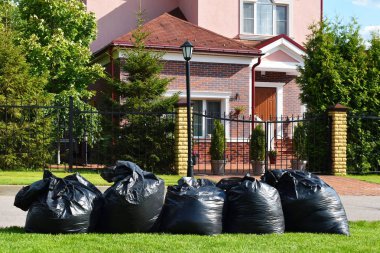Çimenlikte büyük siyah çöp torbası var. Alanın temizlenmesi.
