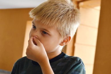 Çocuk burnuna parmağıyla dürtünür. Çocuk dışarı çeker 