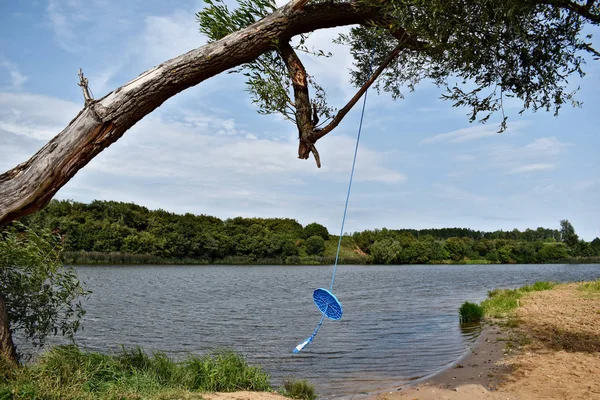 Columpio de cuerda en un árbol por encima del agua. Parque infantil casero en el — Foto de Stock