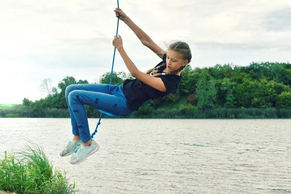 Vrolijk meisje swingend op een touwschommel. Beleef een leuke zomer vacat — Stockfoto