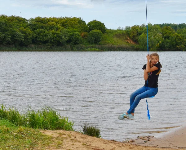 Vrolijk meisje swingend op een touwschommel. Beleef een leuke zomer vacat — Stockfoto