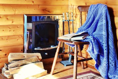 Sobayı olan ahşap bir evin rahat iç. Bir sandalyede ekose 