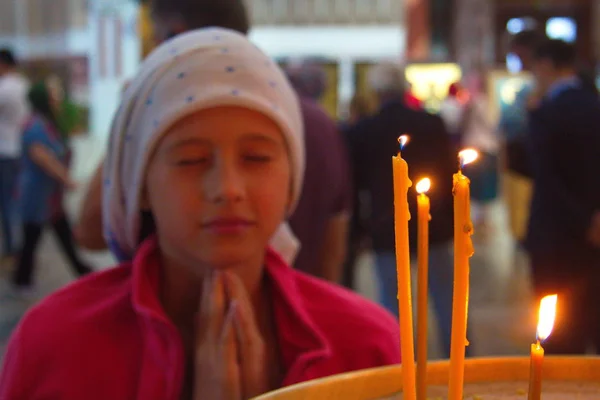 Una chica en la iglesia está rezando. Velas en el templo . — Foto de Stock