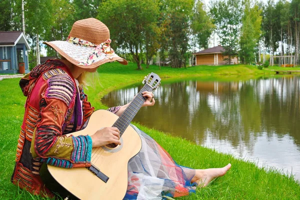 Donna con una chitarra vicino all'acqua. Una persona suona la chitarra in t — Foto Stock