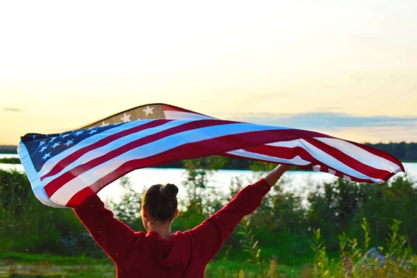 Kobieta z amerykańską flagą wieczorem o zachodzie słońca. — Zdjęcie stockowe