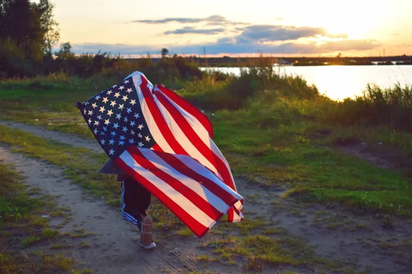 Et barn løber med det amerikanske flag ved solnedgang . - Stock-foto