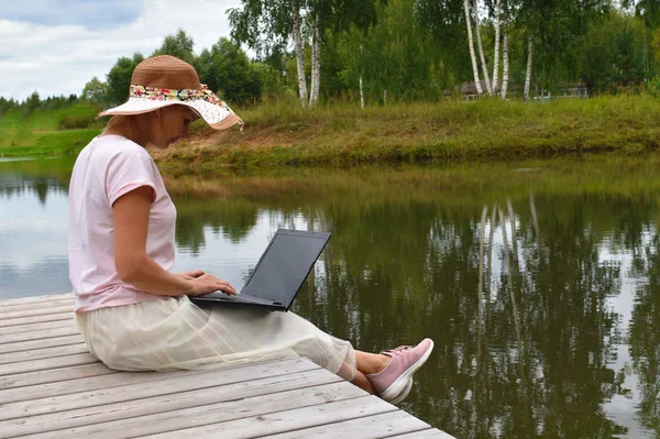 Дівчина з ноутбуком на дерев'яному пірсі . — стокове фото