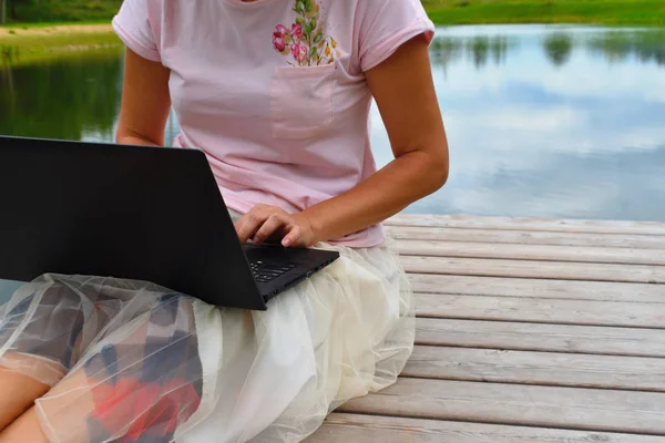 Menina com um laptop em um cais de madeira . — Fotografia de Stock
