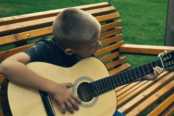 Un ragazzo suona la chitarra nella foresta . — Foto Stock