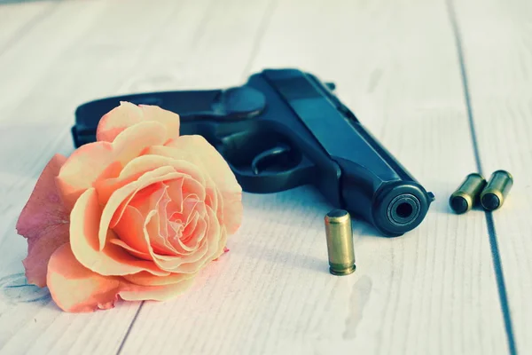 Pistola, flor y cartuchos sobre la mesa. Asesinato y amor . — Foto de Stock