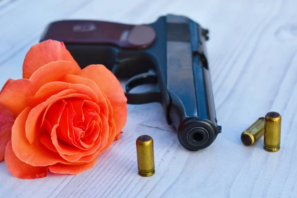 Pistola, flor y cartuchos sobre la mesa. Asesinato y amor . — Foto de Stock