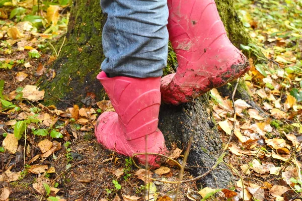 Uma criança em botas de borracha vermelha no outono . — Fotografia de Stock