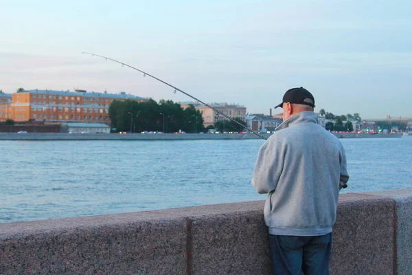 Egy halász horgászik a városi sétányon. Esti halászat a sétányon — Stock Fotó